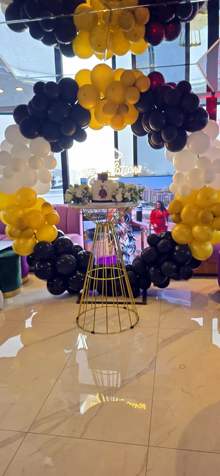 Navy, gold and white balloons around a gold cake stand in a bright room